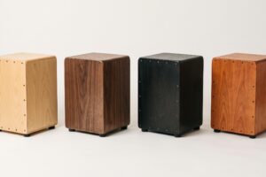 Cuatro cajones peruanos de distintos colores y acabados de madera alineados sobre fondo neutro