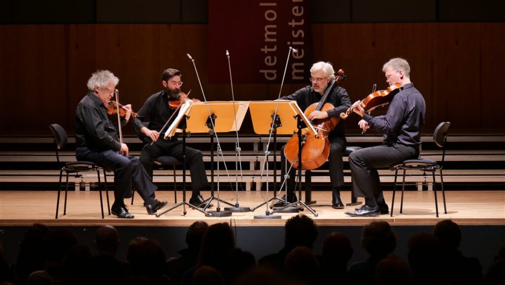 Un cuarteto de cuerda toca en un escenario: dos violines, una viola y un violonchelo