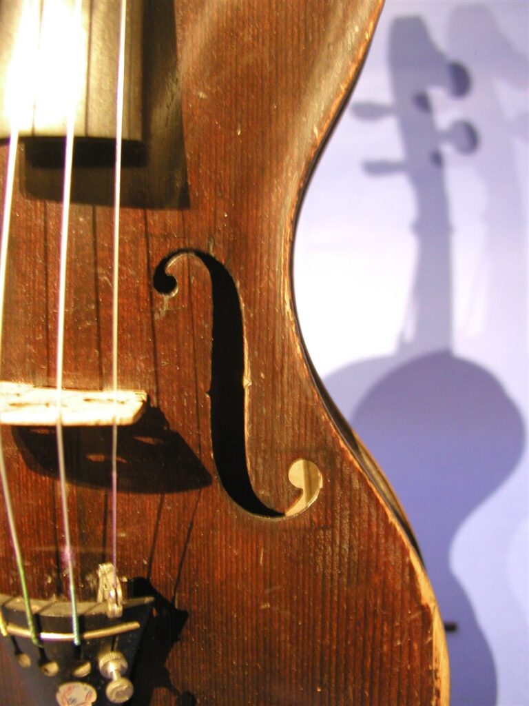 Primer plano de la efe de un viol&iacute;n antiguo, con el puente y las cuerdas a la izquierda