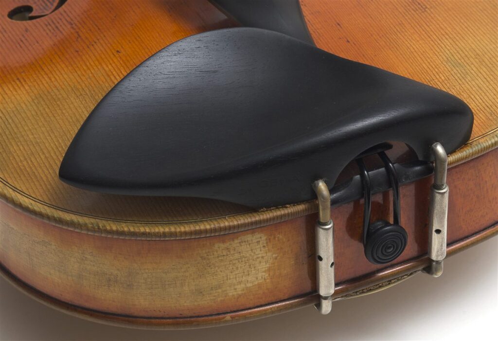 Mentonera negra de un viol&iacute;n sujeta al borde de la caja con dos abrazaderas met&aacute;licas