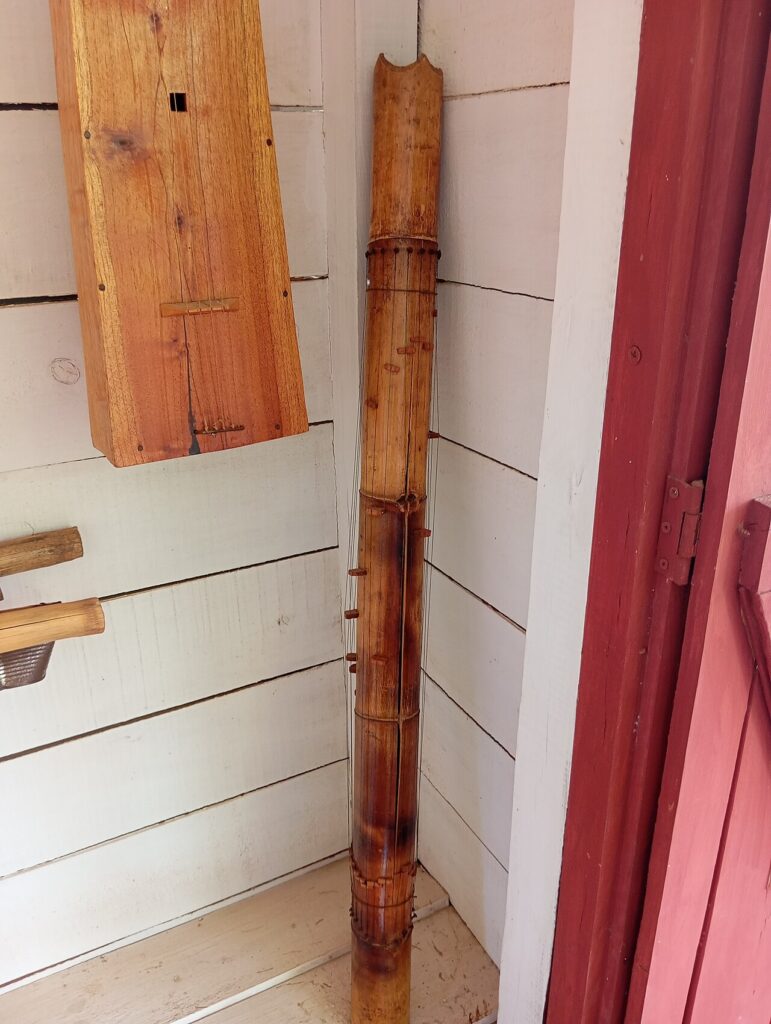 Valiha de bamb&uacute; expuesta en un museo, con las cuerdas alrededor del tubo y los puentecillos