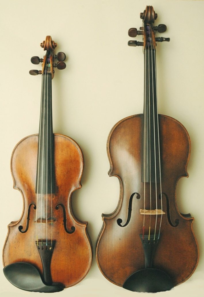 Un violín junto a una viola: la viola es más grande y tiene la caja más ancha